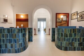 A reception area with two curved blue-tiled counters, a white archway, and framed certificates on the wall.