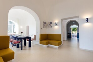 A modern interior with a dining area, a sofa, and a hallway leading to an outdoor area.