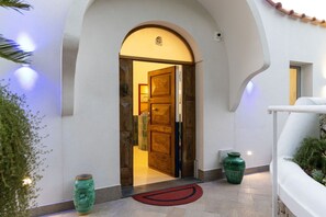 A hotel entrance with a wooden door, a red doormat, and a green vase. - MyExclusiveItaly - Elegant Villa in Anacapri | Infinity Pool & Design (Anacapri)
