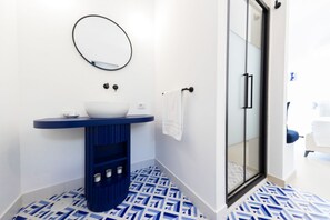 A bathroom with a white sink, blue vanity, patterned floor, and a glass shower door. - MyExclusiveItaly - Elegant Villa in Anacapri | Infinity Pool & Design (Anacapri)