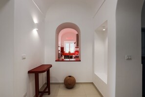 A hallway leading to a kitchen with a red accent wall and a neon sign.