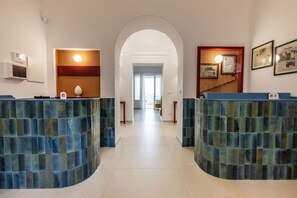 A reception area with two curved blue-tiled counters, a white archway, and framed certificates on the wall.