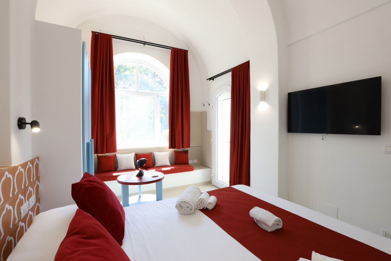 A hotel room with a bed, a small table, a sofa, and a TV.