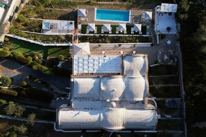 Ein Luftbild eines Hotels mit Schwimmbad, mehreren Terrassen und einem überdachten Außenbereich.