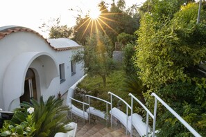 A white building with a curved roof and a stone pathway leading to a white railing.