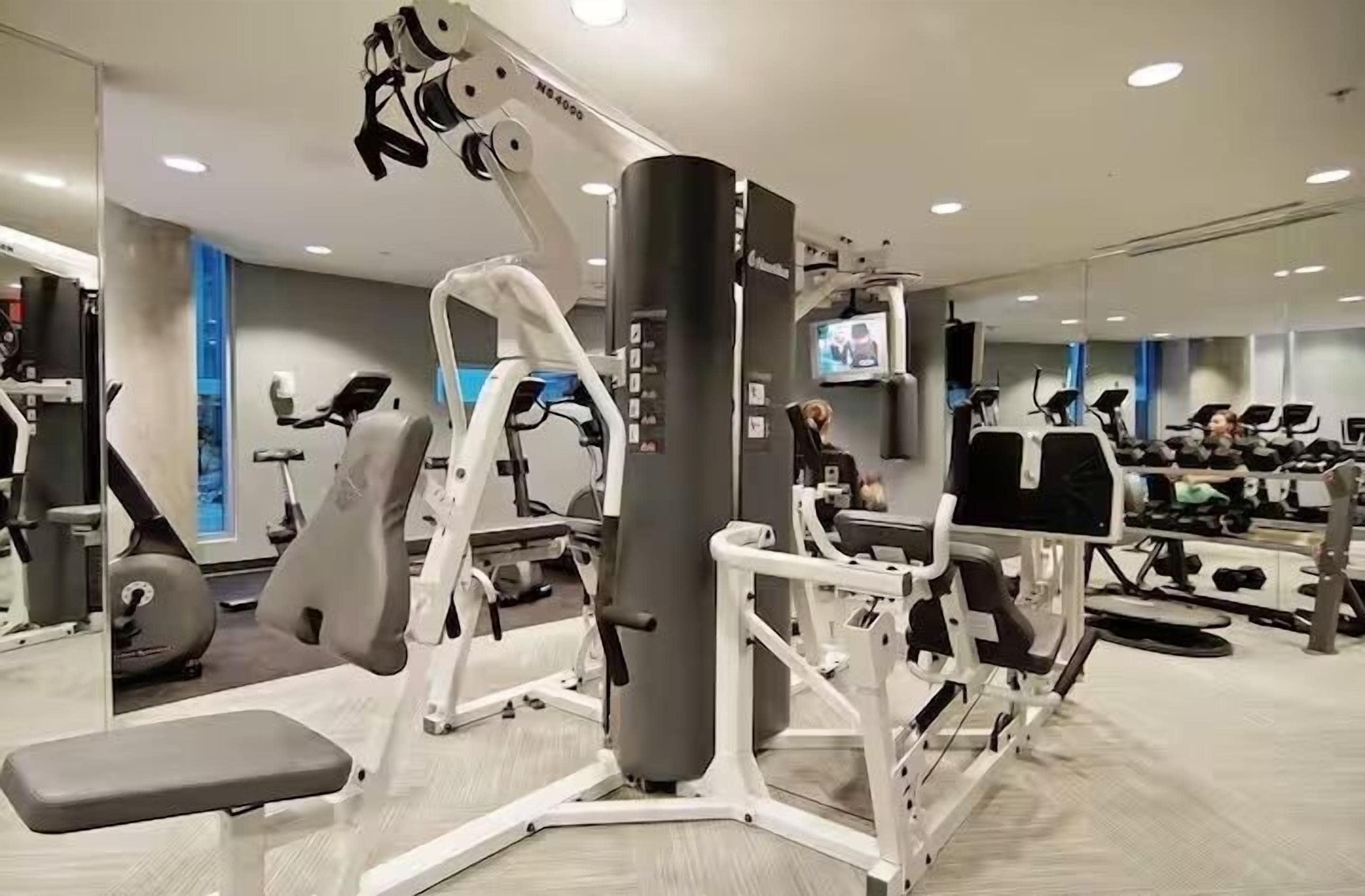 Un gimnasio moderno con diversos equipos de ejercicio, incluyendo cintas de correr, máquinas de pesas y una máquina de remo.