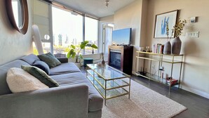 A modern living room with a sofa, TV, and a glass coffee table.