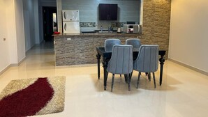 Een moderne keuken met een centraal eiland, inbouwverlichting en een eetgedeelte met een rood en beige vloerkleed.