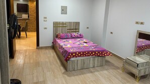 Een slaapkamer met een bed, nachtkastjes, een kledingkast en een klein bureau.