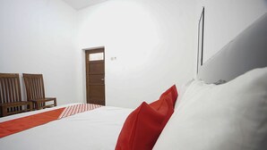 A bedroom with a bed, a wooden door, and two wooden chairs.