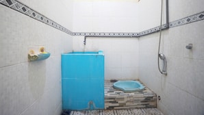 A small bathroom with white tiled walls, a blue sink, a shower, and a toilet.