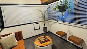 A cozy room with a wooden ceiling, a round wooden table with a chessboard, a sofa, and two stools. - Hot tub, Sauna, adult game room, pool table, house has lots of stairs! (Reno)
