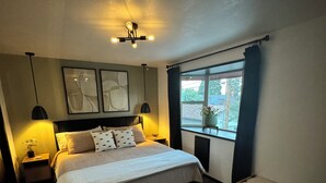 A bedroom with a bed, bedside tables, a bench, a rug, and artwork on the wall. - Hot tub, Sauna, adult game room, pool table, house has lots of stairs! (Reno)