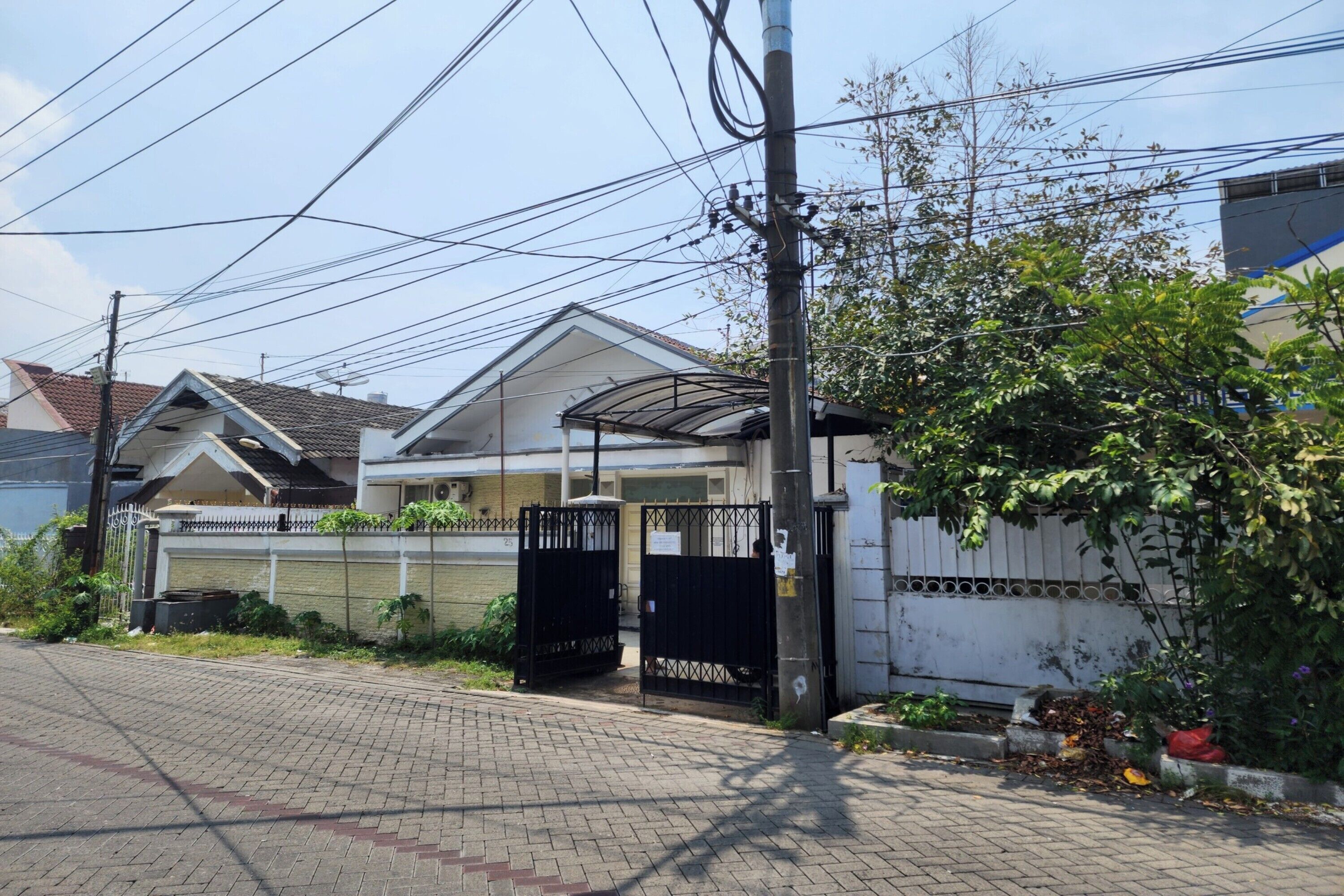 A residential house with a gated entrance, a covered porch, and a brick pathway leading to the front door.
