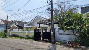 A residential house with a gated entrance, a covered porch, and a brick pathway leading to the front door.