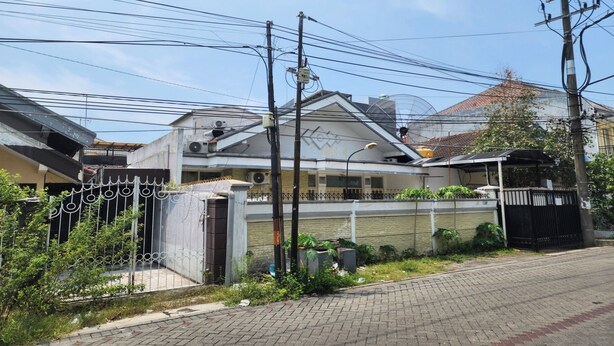 A residential building with a gated entrance, a paved driveway, and multiple utility poles with overhead wires. - OYO Life 93977 Suterejo Homestay Syariah (Surabaya)
