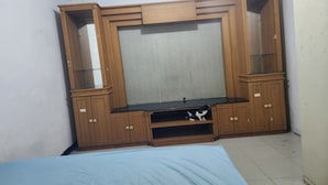 A bedroom with a bed, wooden wardrobe, and a TV stand. - OYO Life 93977 Suterejo Homestay Syariah (Surabaya)