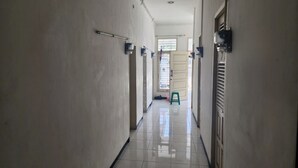 A hallway with white walls, a tiled floor, and a green stool. - OYO Life 93977 Suterejo Homestay Syariah (Surabaya)