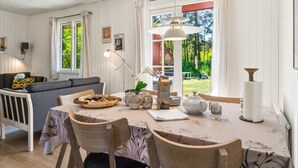 Un coin repas avec une table dressée pour deux personnes, un canapé et une fenêtre avec des rideaux.