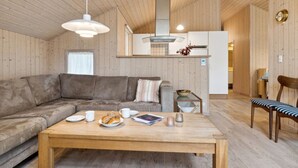 A cozy living room with a wooden ceiling, a sofa, a coffee table with pastries, and a dining area with a chair. - "Ava" - 850m from the sea by Interhome (Nexø)