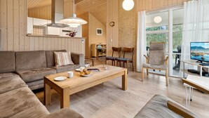 A cozy living room with a sofa, coffee table, and a dining area with chairs and a table. - "Ava" - 850m from the sea by Interhome (Nexø)