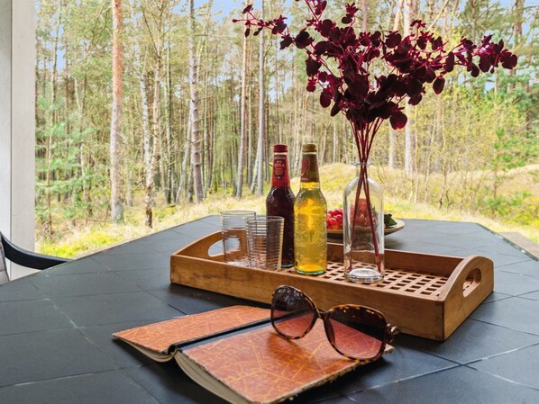 A table with a tray holding a bottle, glasses, a vase with flowers, and a notebook.