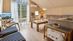 A cozy living room with wooden walls, a large window, a sofa, a coffee table, and a TV. - "Ava" - 850m from the sea by Interhome (Nexø)