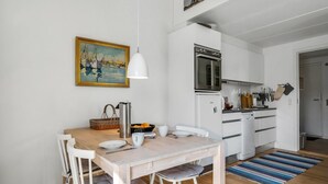 A modern kitchen with white cabinets, a stainless steel oven, and a hanging pot rack.