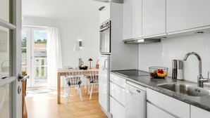A modern kitchen with white cabinets, a stainless steel sink, and a built-in oven.
