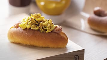 A hot dog on a bun with mustard and sauerkraut on a wooden surface.