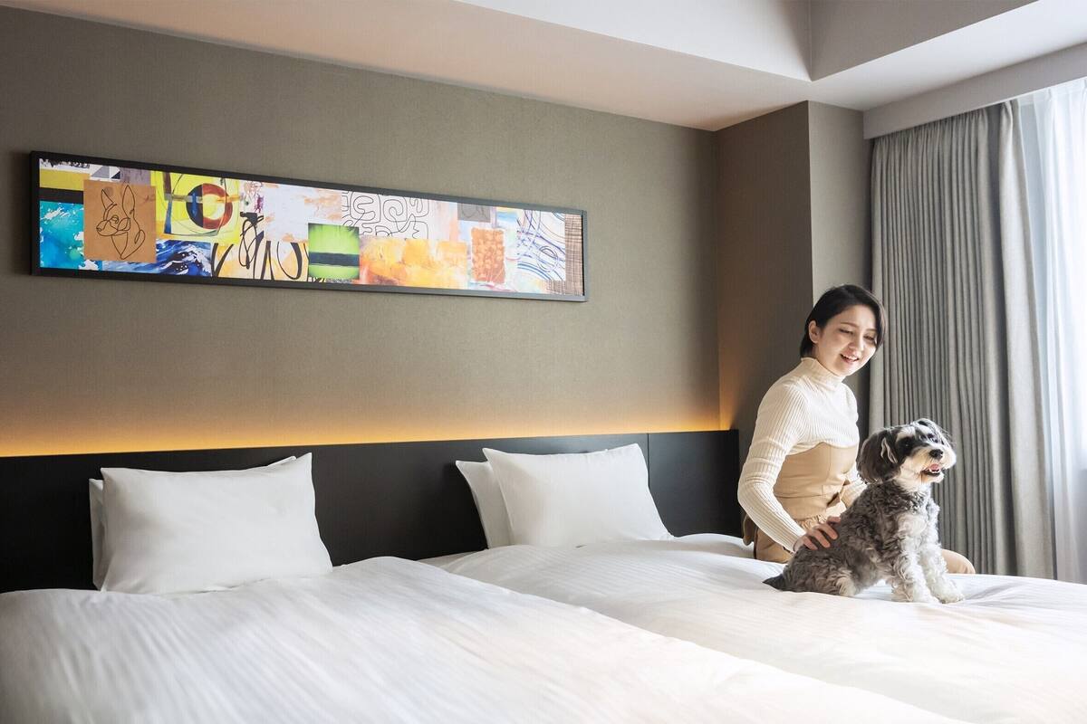 Ein Hotelzimmer mit einem großen Bett, einem Kopfteil und einer Wand mit einem farbenfrohen abstrakten Gemälde.