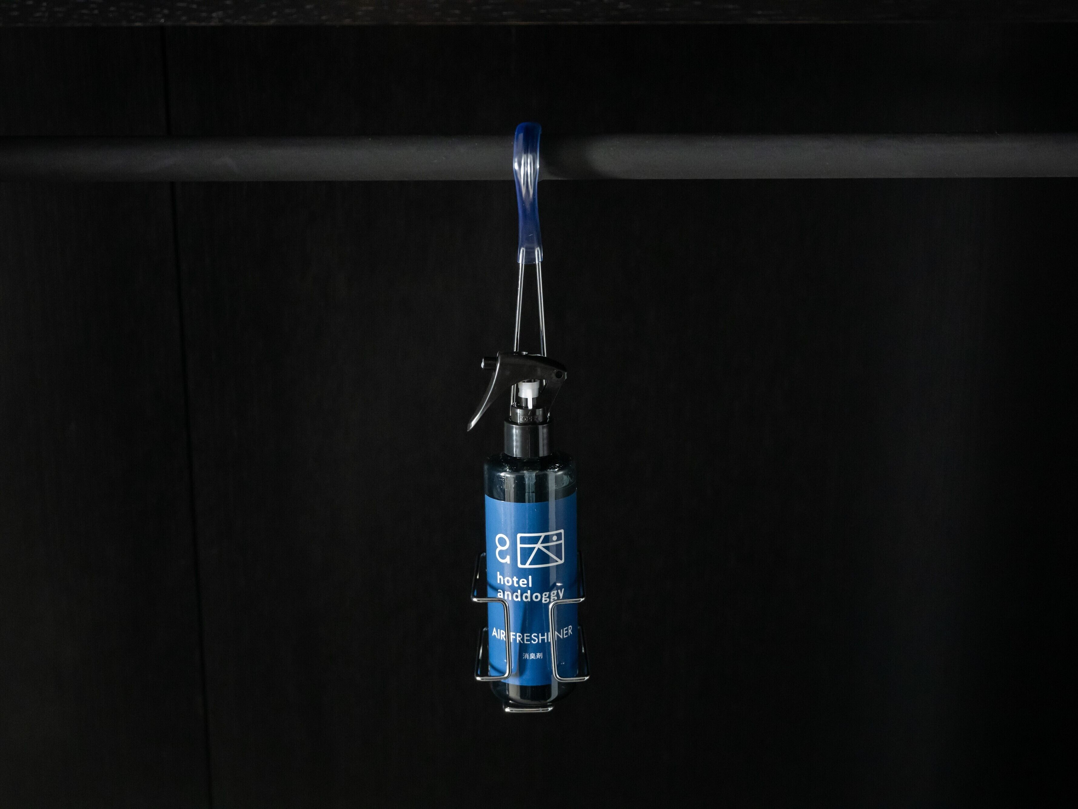 Un ambientador azul colgando de una pared negra.