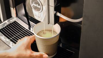 Une main tenant une tasse sous une machine à café qui verse du café.