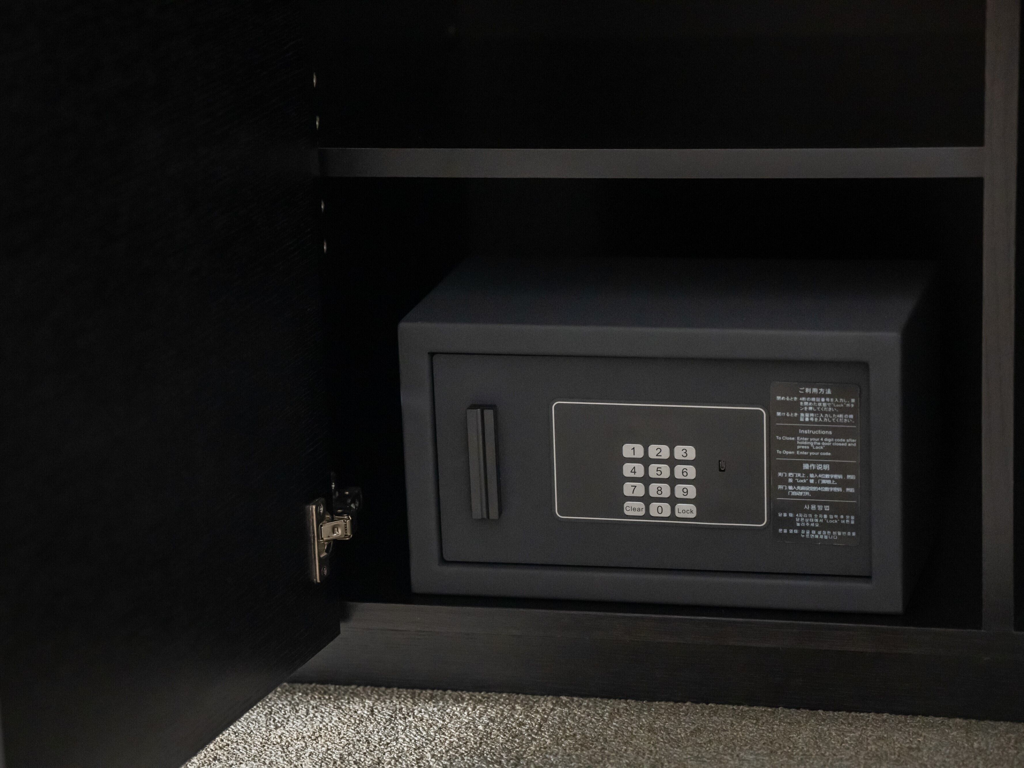 A black safe with a keypad and instructions in multiple languages.