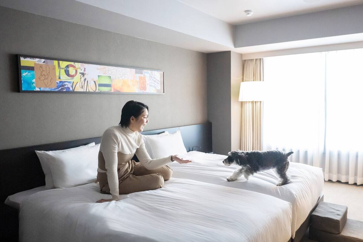 Ein Hotelzimmer mit einem großen Bett, einem Bild an der Wand und einem Fenster mit Vorhängen.