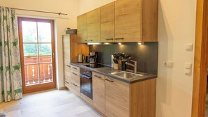 A modern kitchen with wooden cabinets, a stainless steel sink, and a built-in oven. - Ferienwohnung Kampenwand (Bernau am Chiemsee)