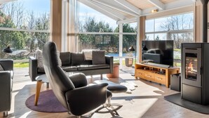 A modern living room with a black leather sofa, a TV, and a wood-burning stove. - "Anastaja" - 550m from the sea by Interhome (Jerup)