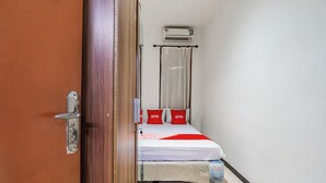 Quarto de hotel com cama, cortina, ar condicionado e porta.