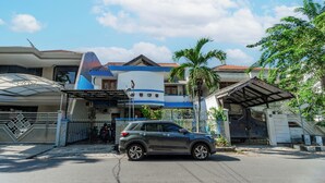 Um edifício moderno com portão fechado, um SUV estacionado e um céu azul claro.