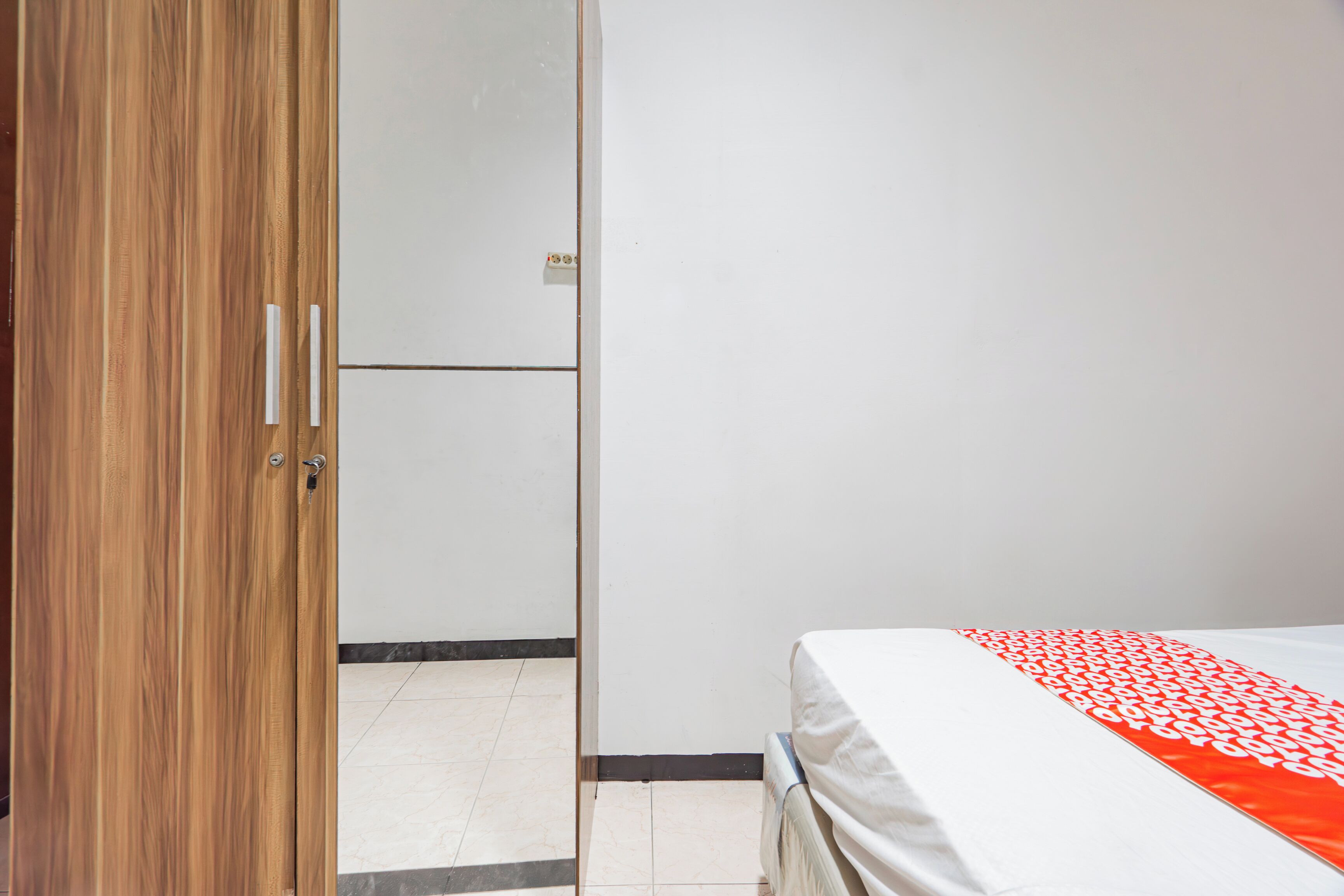 Een slaapkamer met een bed, een houten garderobe en een witte muur.