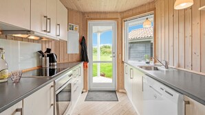 A modern kitchen with wooden paneling, stainless steel appliances, and a view through a glass door. - "Aurelie" -  from the sea by Interhome (Ulfborg)