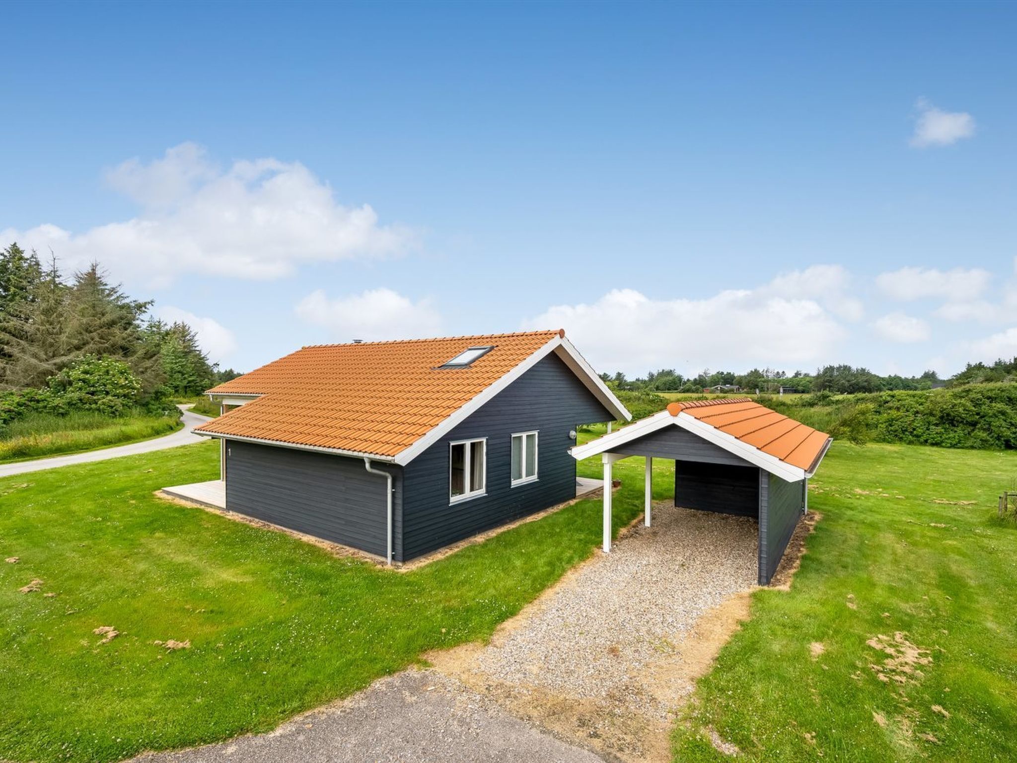 Une maison moderne à deux étages, avec une façade bleu foncé et un toit recouvert de tuiles rouges.