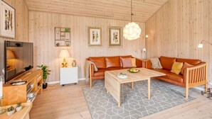 A cozy living room with a wooden ceiling, a brown leather sofa, a wooden coffee table, and a TV on a wooden stand. - "Aurelie" -  from the sea by Interhome (Ulfborg)