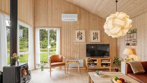 A cozy living room with a fireplace, a TV, and a large window overlooking a garden. - "Aurelie" -  from the sea by Interhome (Ulfborg)