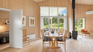 A wooden interior with a dining area, a fireplace, and large windows. - "Aurelie" -  from the sea by Interhome (Ulfborg)