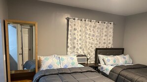 Un dormitorio con dos camas, un armario, un espejo y una ventana con cortinas estampadas.