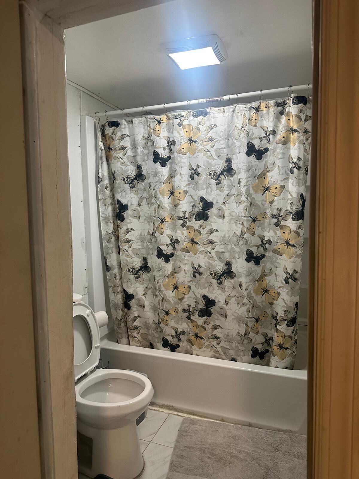 A bathroom with a toilet, a bathtub, and a shower curtain with a floral pattern.