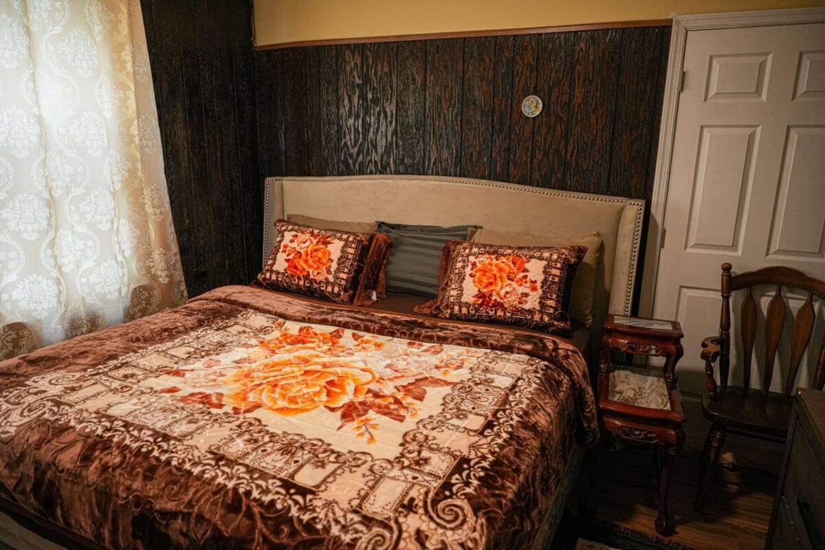 Een slaapkamer met een groot bed, een houten hoofdbord en een nachtkastje met een lamp.