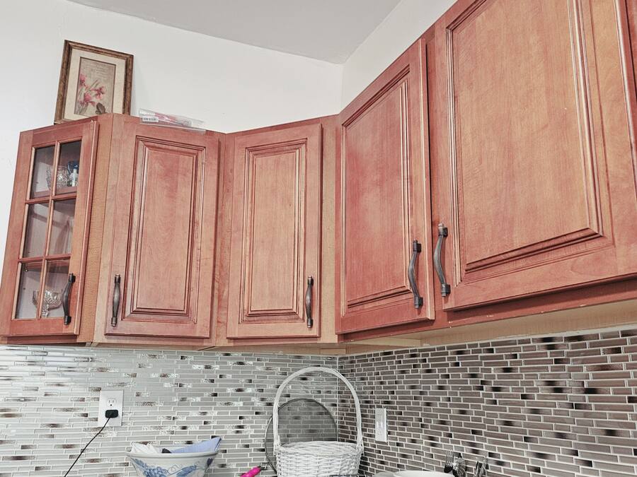 A kitchen with wooden cabinets, a tiled backsplash, and various kitchen items on the counter.