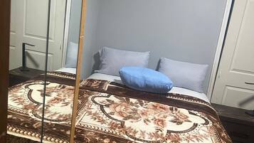 A bedroom with a bed, a mirror, and a door.